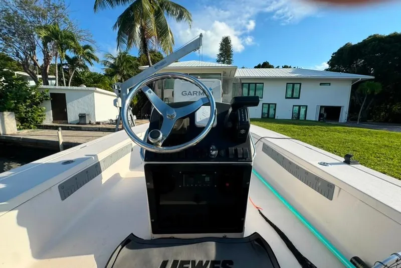 Slide: The Image of 2003 Hewes Redfisher 21 boat interior with steering wheel, docked near a modern house. - 8