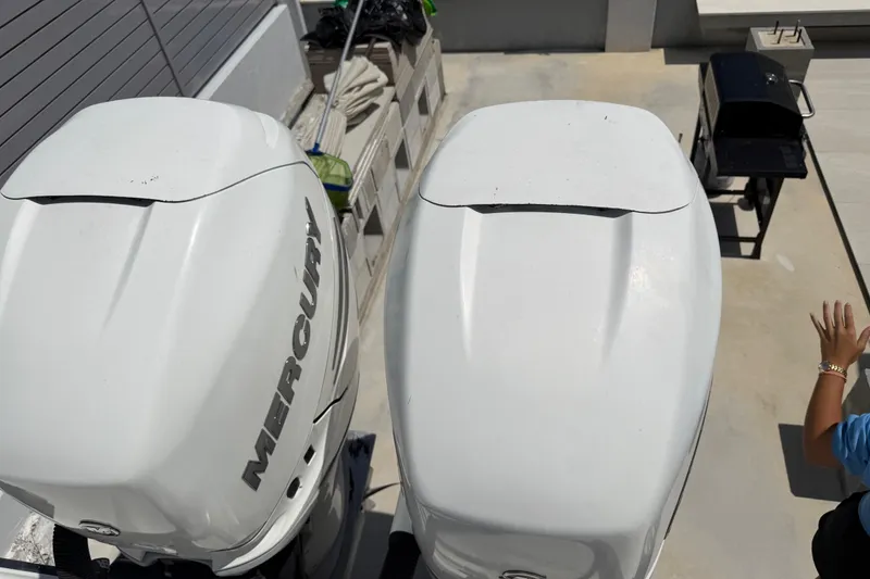 Slide: The Image of Two large outboard motors on a boat, with a grill in the background. - 14