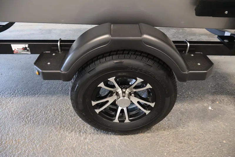 Slide: The Image of 2027 Lowe Fishing Machine 1675WT trailer wheel with black fender on concrete floor. - 47