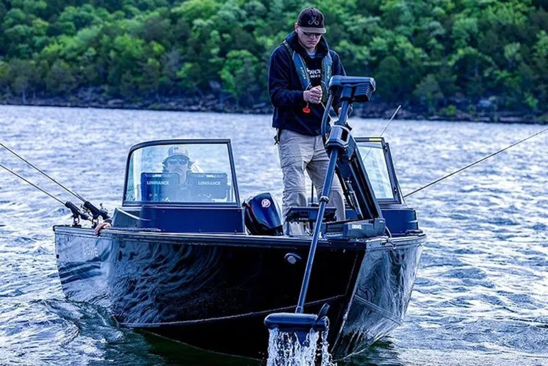 Slide: The Image of 2026 Lowe Fishing Machine 1875 on a lake, two people fishing, surrounded by lush greenery. - 1