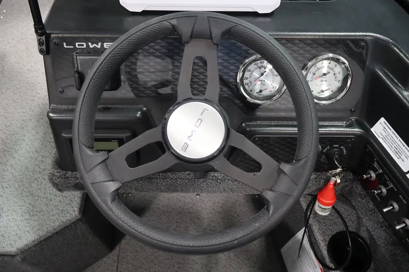 Slide: The Image of Steering wheel and dashboard of 2027 Lowe Fishing Machine 1875 boat, featuring gauges and controls. - 18