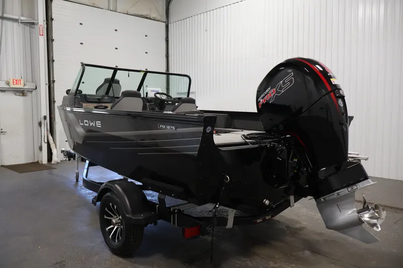 Slide: The Image of 2027 Lowe Fishing Machine 1875 boat with powerful outboard motor in a garage setting. - 6