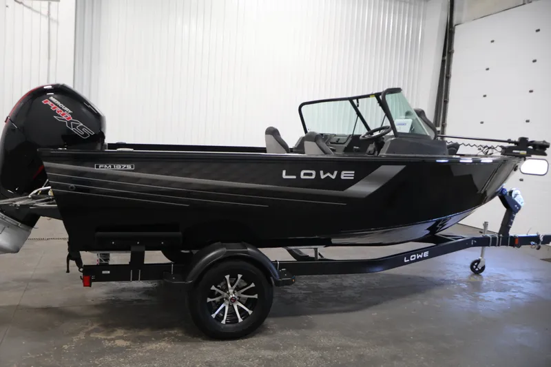 Slide: The Image of 2027 Lowe Fishing Machine 1875 boat in showroom, featuring sleek black design and powerful engine. - 3