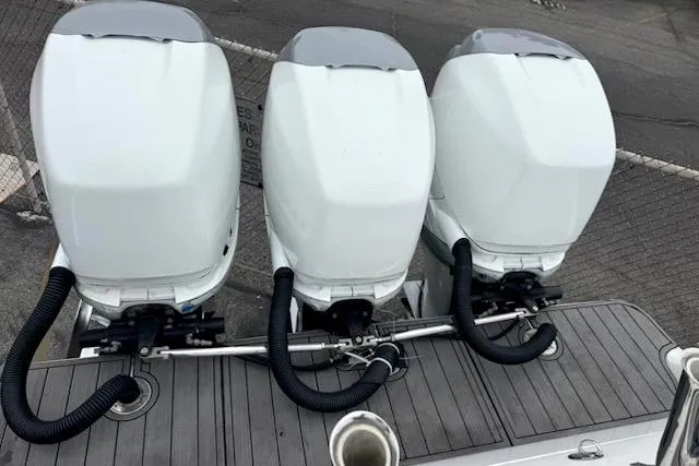 Slide: The Image of Triple outboard motors on a 2016 Mystic M4200 boat, docked on a wooden platform. - 4