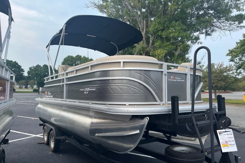 The Image of 2025 Sun Tracker Party Barge 20 DLX pontoon boat on trailer, parked outdoors. - 0