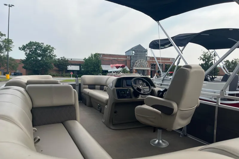 Slide: The Image of 2025 Sun Tracker Party Barge 20 DLX interior with plush seating and steering console. - 7