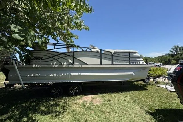 Slide: The Image of 2022 Lexington 623 pontoon boat on trailer, parked on grass under a tree. - 3