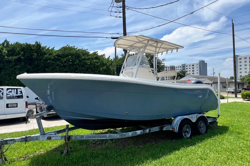 The Image of 2019 Cobia 220 Center Console boat on trailer, parked outdoors under clear sky. - 1