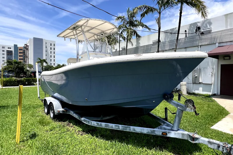 Slide: The Image of 2019 Cobia 220 Center Console boat on trailer, parked on grass near palm trees. - 10