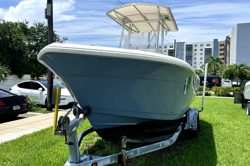 Slide: The Image of 2019 Cobia 220 Center Console boat on trailer, parked on grass. - 11