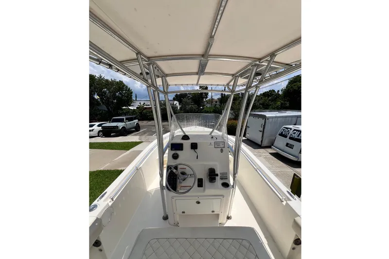 Slide: The Image of 2019 Cobia 220 Center Console boat interior with steering wheel and controls, parked outdoors. - 12