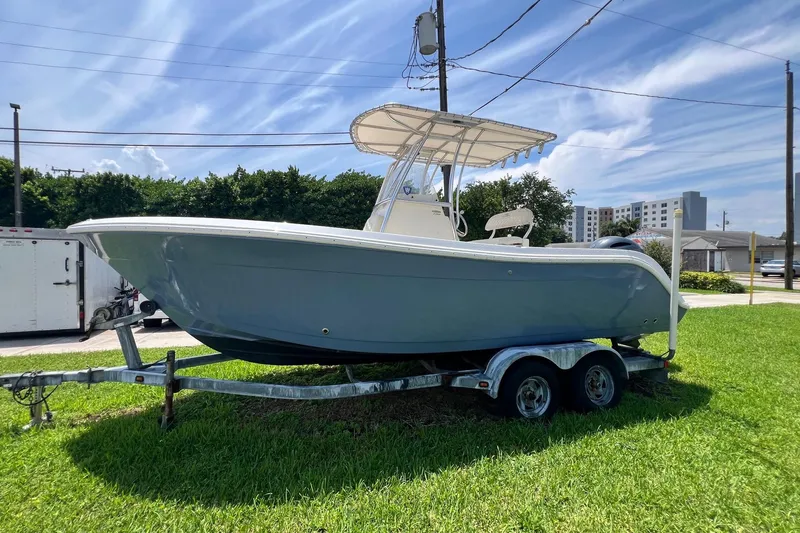 Slide: The Image of 2019 Cobia 220 Center Console boat on trailer, parked on grass under clear sky. - 5