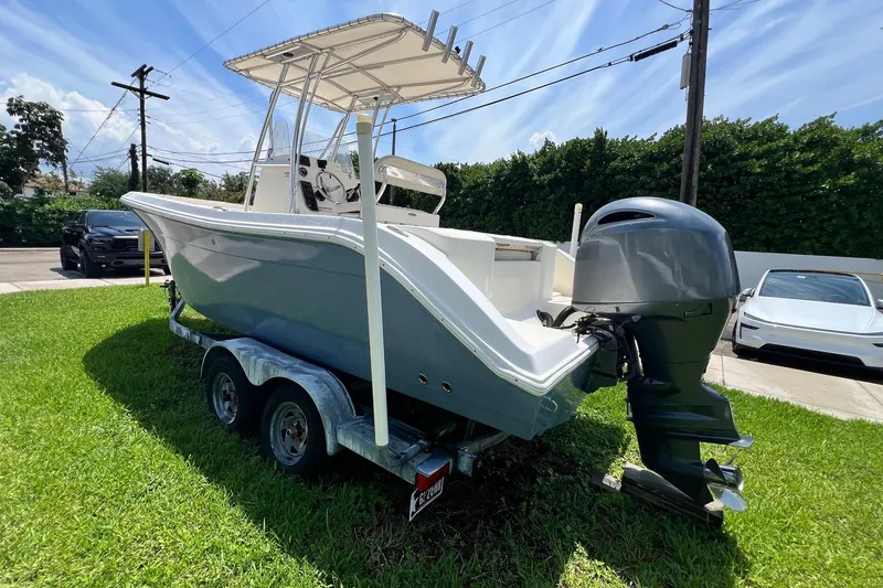 Slide: The Image of 2019 Cobia 220 Center Console boat on trailer, parked on grass under a sunny sky. - 6