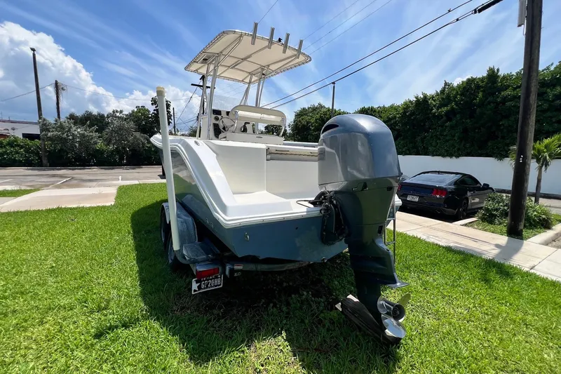 Slide: The Image of 2019 Cobia 220 Center Console boat on trailer, parked on grass under a sunny sky. - 7