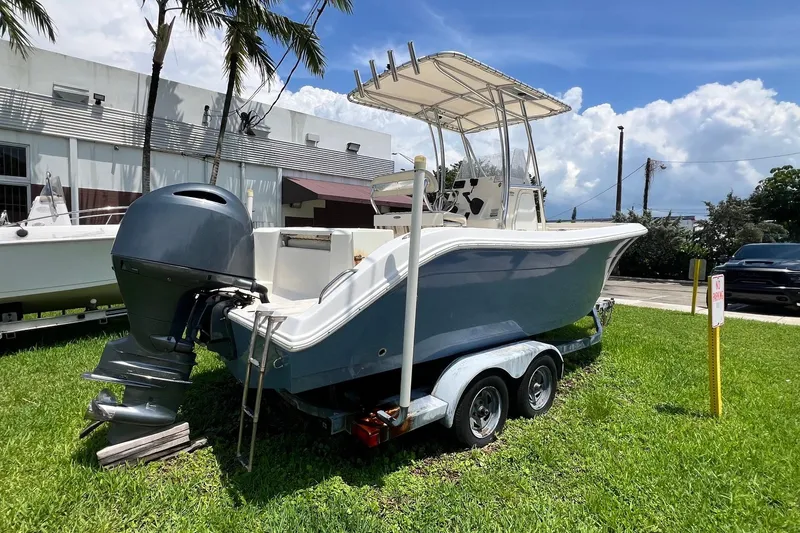 Slide: The Image of 2019 Cobia 220 Center Console boat on trailer, parked on grass under clear sky. - 8