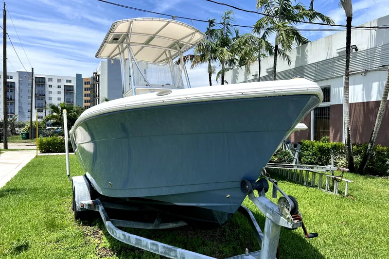 Slide: The Image of 2019 Cobia 220 Center Console boat on trailer, parked on grass with palm trees. - 9