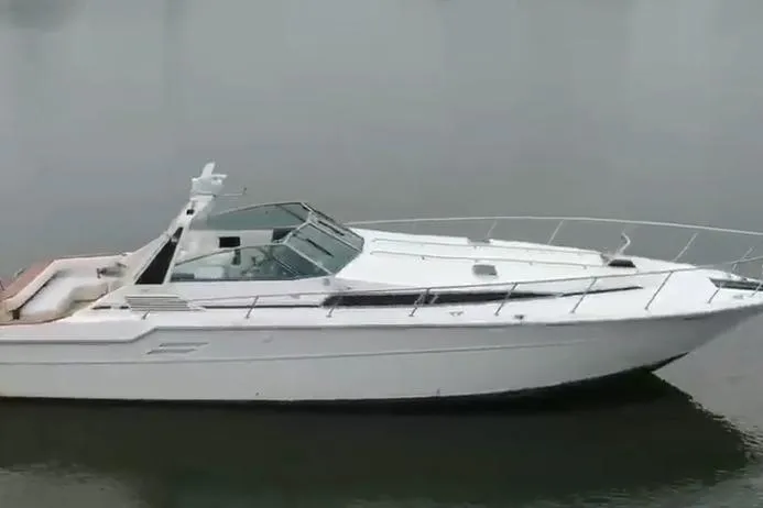 Slide: The Image of 1988 Sea Ray Sundancer 460 yacht on calm water, showcasing sleek design and spacious deck. - 3
