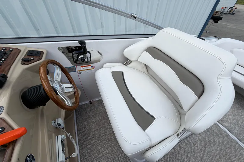Slide: The Image of 2015 Glastron GS 289 boat interior with white and gray seating, wooden steering wheel. - 13