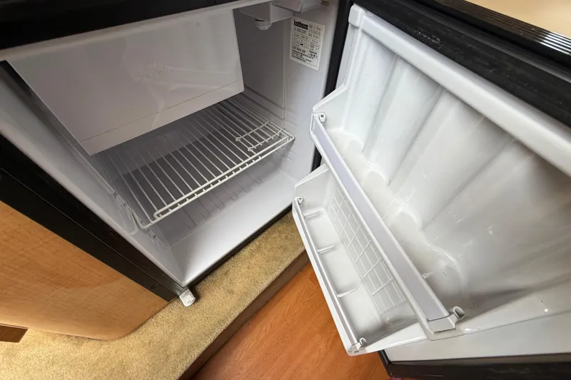 Slide: The Image of Open refrigerator inside a 2015 Glastron GS 289 boat, showing empty shelves. - 18