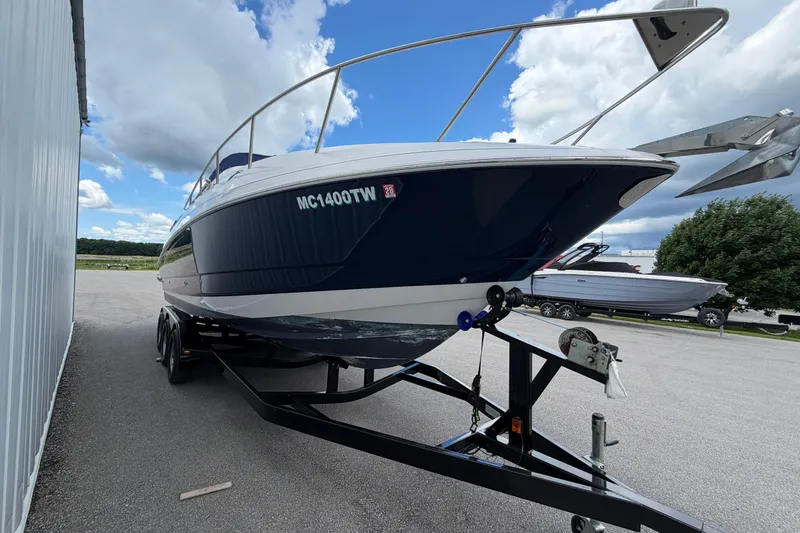 Slide: The Image of 2015 Glastron GS 289 boat on trailer, parked outdoors under a cloudy sky. - 2