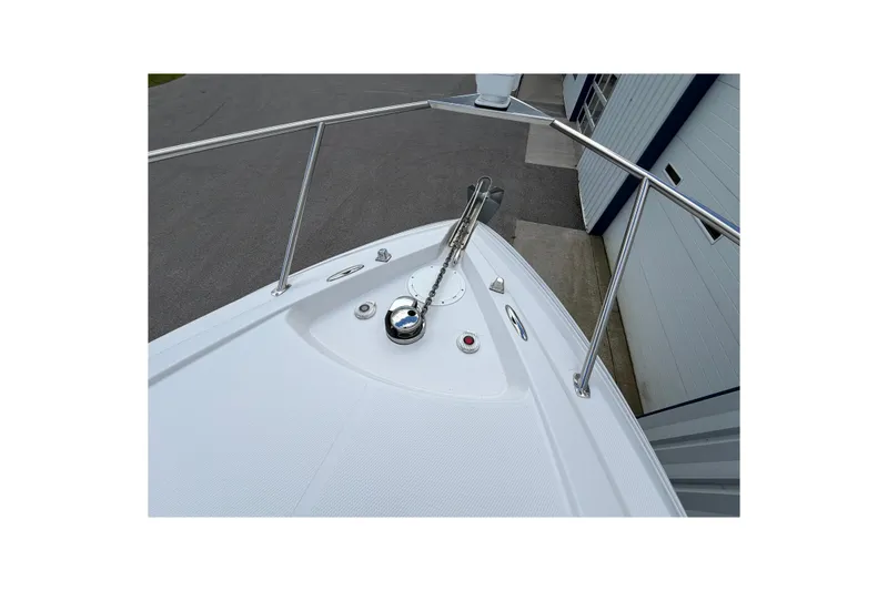 Slide: The Image of 2015 Glastron GS 289 boat bow with anchor and railing, docked near a building. - 24