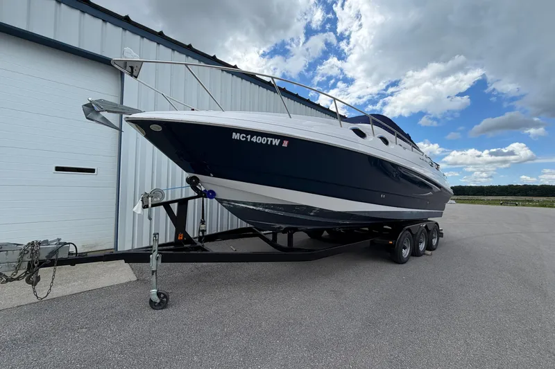Slide: The Image of 2015 Glastron GS 289 boat on trailer, parked near a building under a cloudy sky. - 3