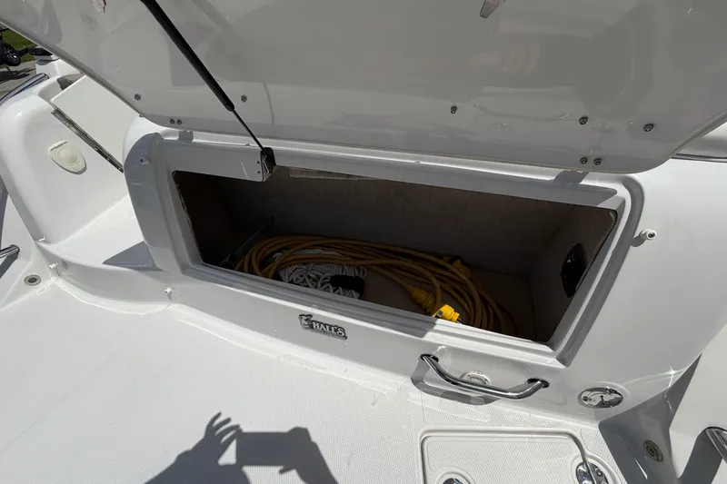Slide: The Image of Open storage compartment on 2015 Glastron GS 289 boat, containing coiled yellow cable. - 8