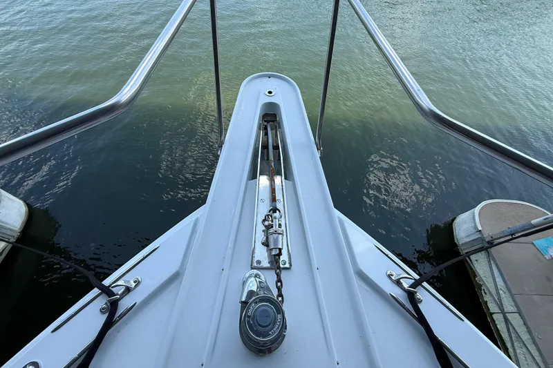 Slide: The Image of Bow of a 1998 Hatteras boat with anchor chain, docked on calm water. - 10