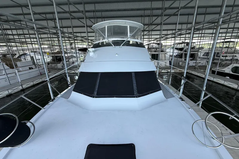 Slide: The Image of 1998 Hatteras yacht docked in a covered marina, showcasing sleek design and spacious deck. - 11