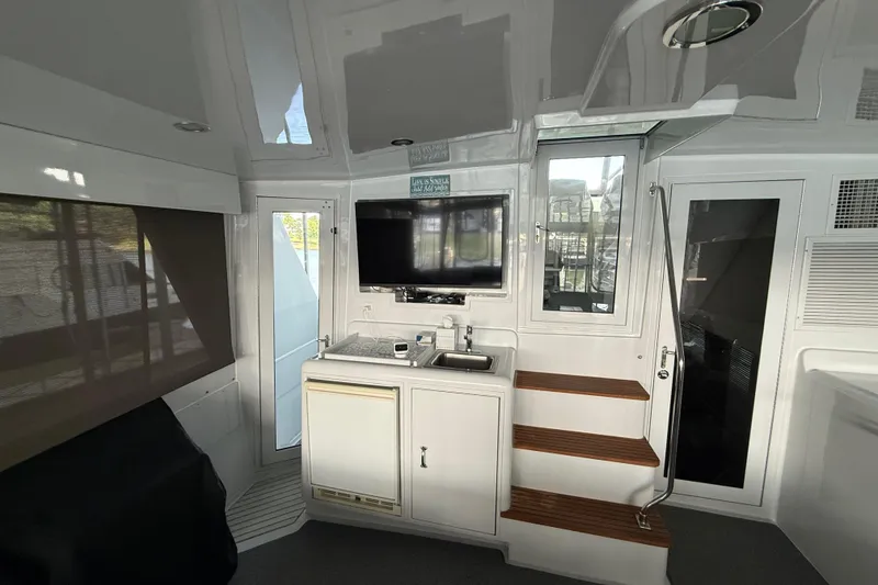 Slide: The Image of Interior of a 1998 Hatteras yacht featuring a kitchenette, TV, and wooden steps. - 18