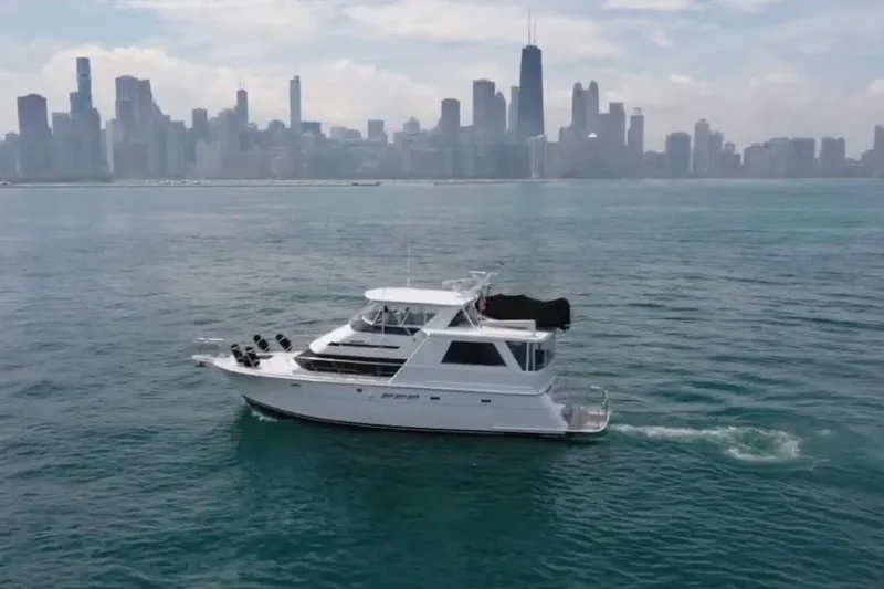 Slide: The Image of 1998 Hatteras yacht cruising on water with city skyline in the background. - 2