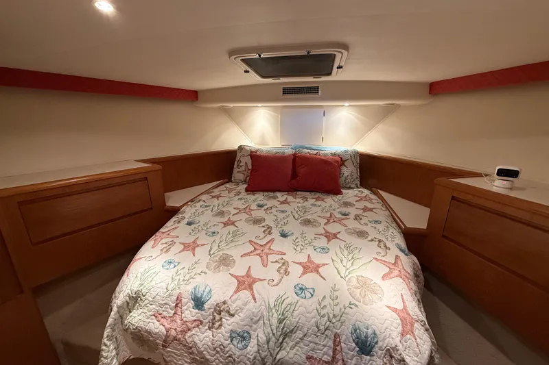Slide: The Image of Cozy 1998 Hatteras yacht bedroom with starfish-themed bedding and wooden cabinetry. - 35
