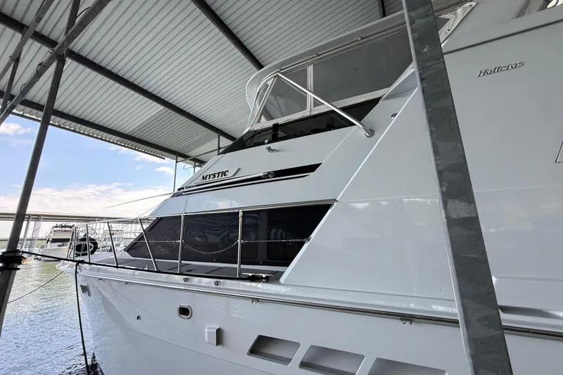 Slide: The Image of 1998 Hatteras yacht named "Mystic" docked under a covered marina. - 8