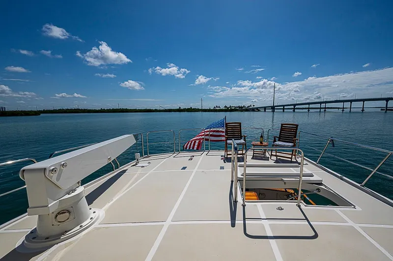 Slide: The Image of 2014 Marlow 80 Explorer yacht deck with chairs, American flag, and ocean view. - 72