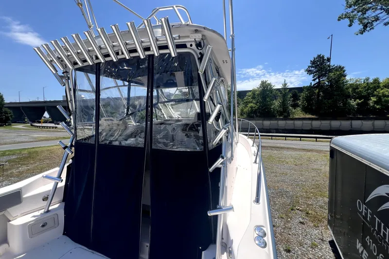 Slide: The Image of 2002 Grady-White Marlin 300 boat with rod holders and clear enclosure, parked outdoors. - 7