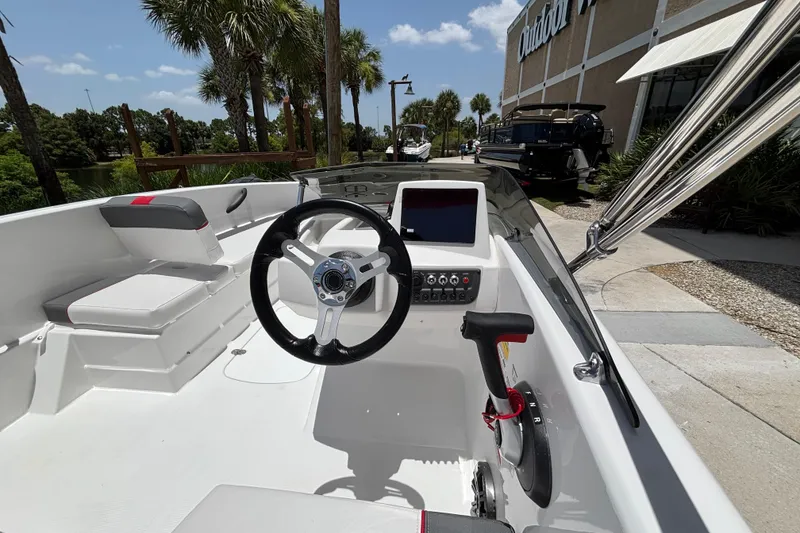 Slide: The Image of 2026 Tahoe T16 boat interior with steering wheel and control panel, parked outdoors. - 62