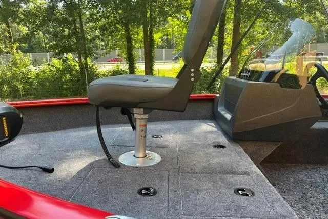 Slide: The Image of 2026 Tracker Pro Guide V-16 SC boat interior with seating and console, surrounded by lush greenery. - 10