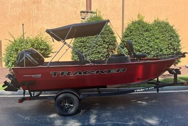 The Image of 2026 Tracker Pro Guide V-16 SC boat with canopy on trailer, parked outdoors. - 0