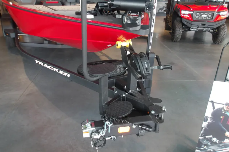 Slide: The Image of 2026 Tracker Savage 215 boat on trailer in showroom, featuring red hull and equipment. - 19