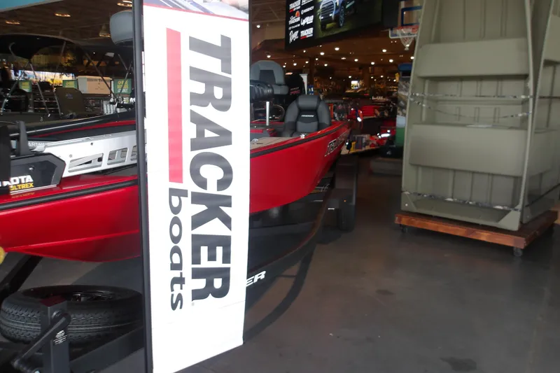 Slide: The Image of 2026 Tracker Savage 215 boat displayed indoors with promotional banner. - 10