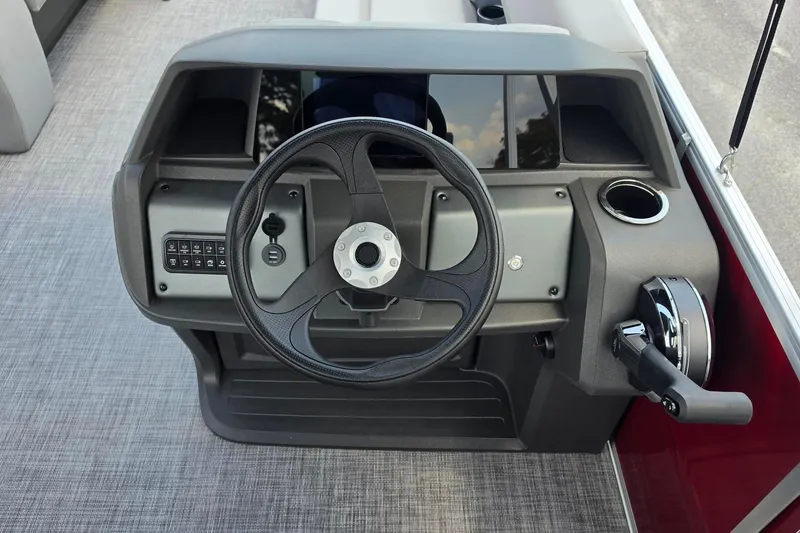 Slide: The Image of Steering console of 2026 Sun Tracker Party Barge 18 DLX with control panel and cup holder. - 13