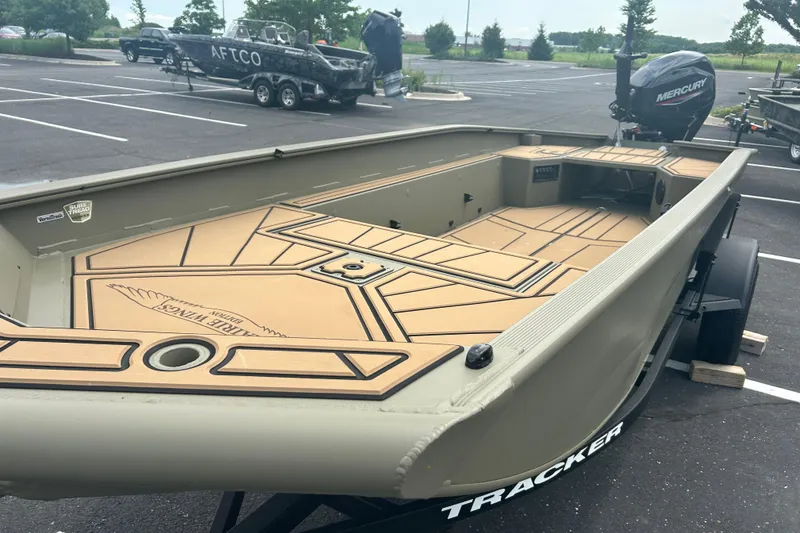 Slide: The Image of 2026 Tracker Grizzly 1650 T Prairie Wings Edition boat in parking lot, featuring spacious deck. - 13