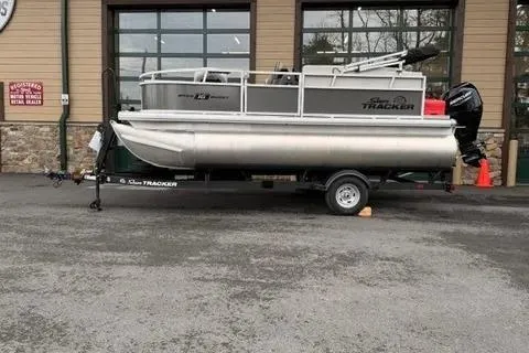 The Image of 2026 Sun Tracker Bass Buggy 16 XL Select pontoon boat on trailer outside dealership. - 0
