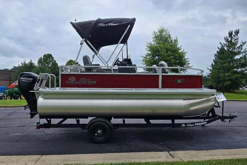 Slide: The Image of 2026 Sun Tracker Bass Buggy 16 XL Select pontoon boat on trailer, parked outdoors. - 5