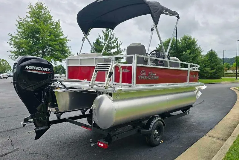 Slide: The Image of 2026 Sun Tracker Bass Buggy 16 XL Select pontoon boat with Mercury engine on trailer. - 2