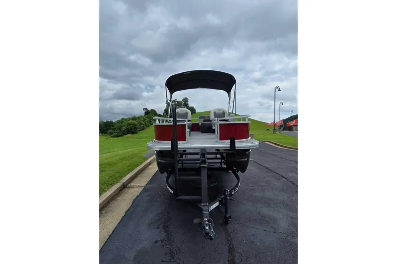 Slide: The Image of 2026 Sun Tracker Bass Buggy 16 XL Select pontoon boat on trailer, parked on paved road. - 4