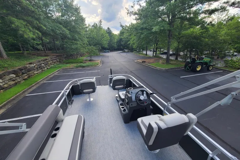 Slide: The Image of 2026 Sun Tracker Bass Buggy 18 DLX pontoon boat parked in a scenic lot. - 14