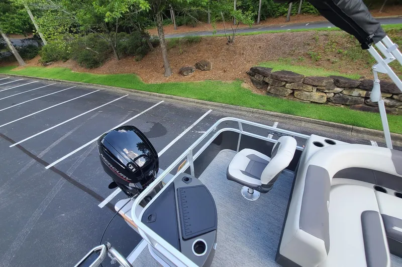 Slide: The Image of 2026 Sun Tracker Bass Buggy 18 DLX pontoon boat in parking lot, featuring seating and motor. - 12