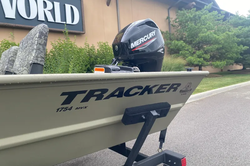 Slide: The Image of 2026 Tracker Grizzly 1754 SC boat with Mercury engine, parked outdoors. - 2