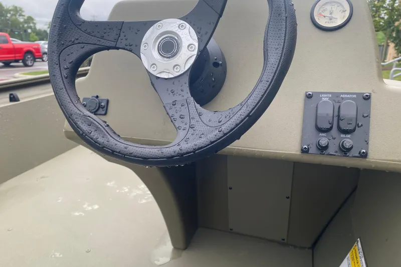 Slide: The Image of Steering wheel and controls of 2026 Tracker Grizzly 1754 SC boat, wet from rain. - 4
